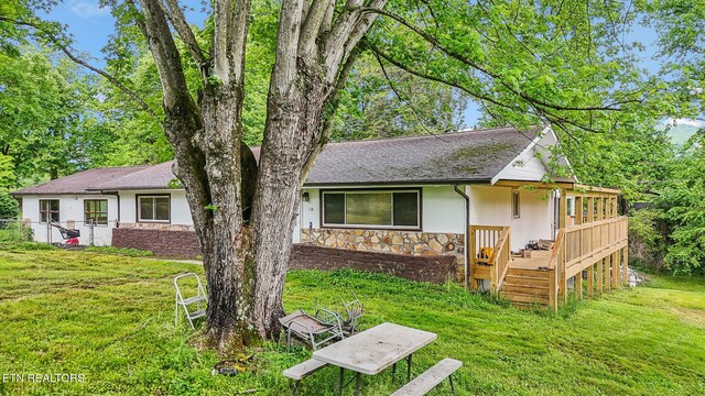 138 Lilac Dr, Lafollette, TN 37766 - ranch-style house with stone siding, a front yard, a deck, and stucco siding