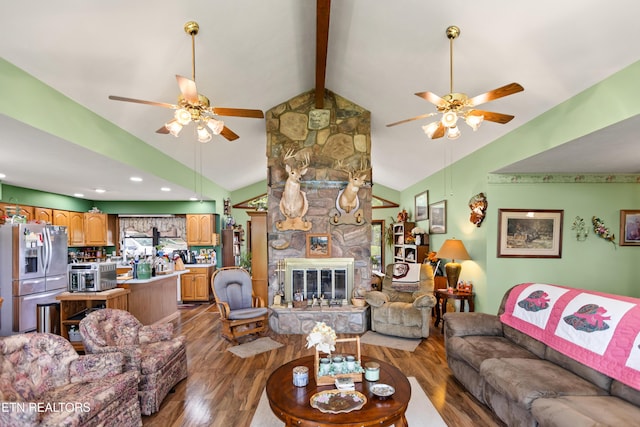 living area with a ceiling fan, wood finished floors, a stone fireplace, and recessed lighting