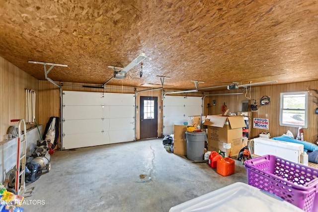 garage with a garage door opener and wood walls