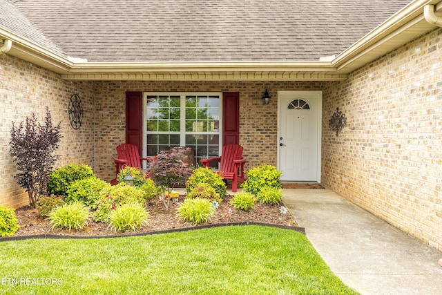 property entrance featuring roof with shingles, covered porch, and brick siding