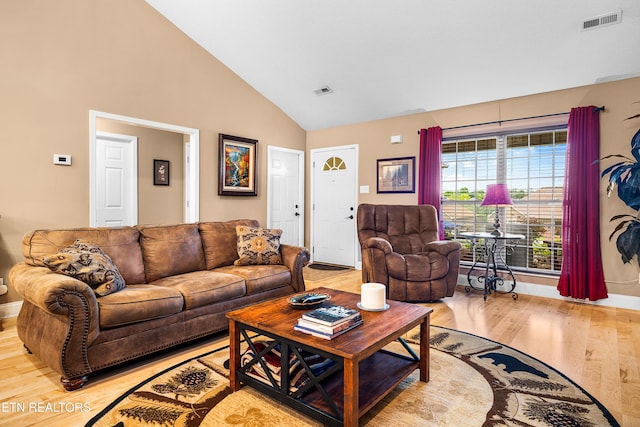 living room featuring light wood-style flooring, high vaulted ceiling, and baseboards
