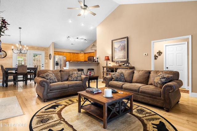 living room featuring a chandelier, light wood finished floors, ceiling fan, high vaulted ceiling, and baseboards