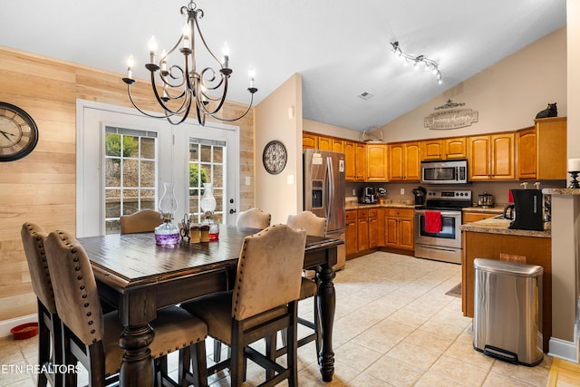 kitchen featuring stainless steel appliances, a chandelier, brown cabinets, lofted ceiling, and light tile patterned floors
