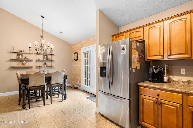 kitchen featuring stainless steel refrigerator with ice dispenser, vaulted ceiling, a chandelier, light tile patterned flooring, and brown cabinetry
