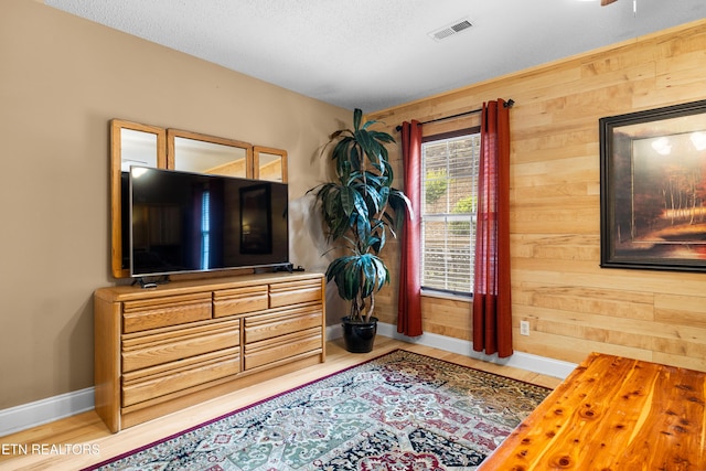 sitting room with baseboards, wooden walls, wood finished floors, and a textured ceiling