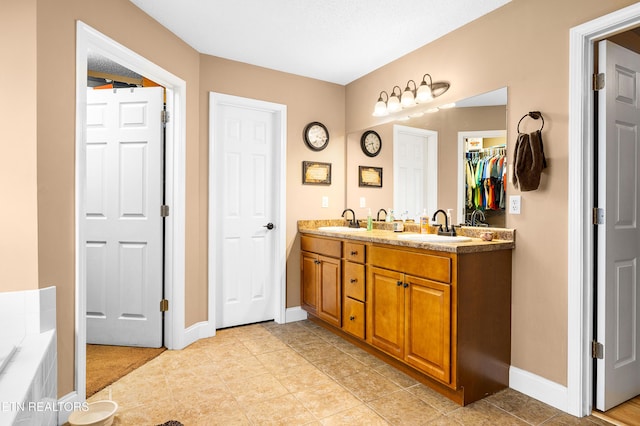 full bath with baseboards, double vanity, a bath, and tile patterned flooring
