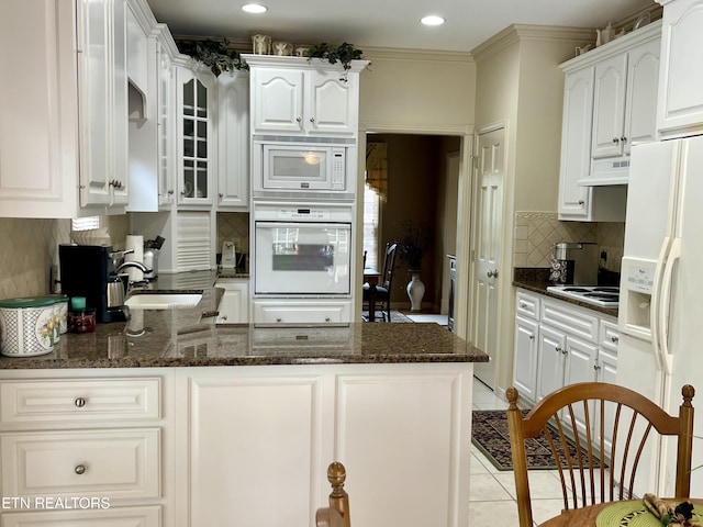 kitchen featuring white appliances, under cabinet range hood, a peninsula, a sink, and white cabinetry