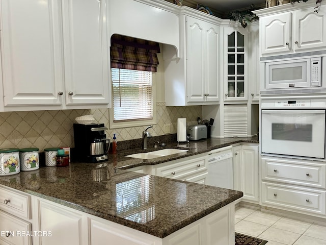 kitchen with white appliances, white cabinets, a sink, and dark stone counters