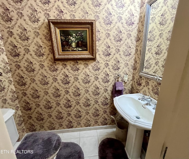 half bath with baseboards, tile patterned floors, and wallpapered walls