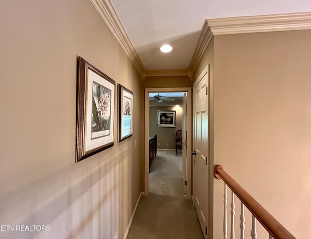 hallway with an upstairs landing, crown molding, carpet flooring, and baseboards