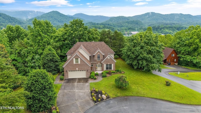 704 Blue Dun Ct, Pigeon Forge, TN 37863 - view of front facade featuring concrete driveway, an attached garage, a mountain view, brick siding, and a front yard