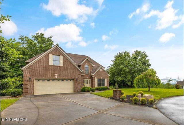 704 Blue Dun Ct, Pigeon Forge, TN 37863 - traditional-style house with driveway, brick siding, a front yard, and an attached garage