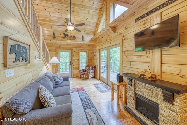 living area with wooden walls, light wood finished floors, healthy amount of natural light, a ceiling fan, and wooden ceiling
