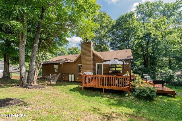 rear view of property featuring a lawn, a chimney, and fence