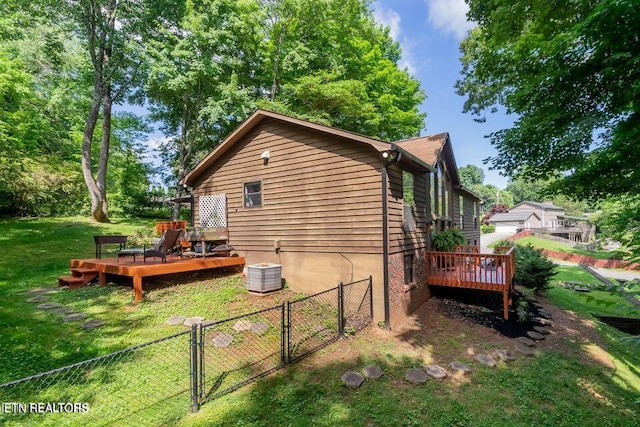 view of side of property featuring fence, a gate, a deck, and a lawn