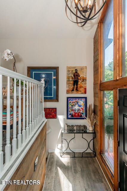 stairs featuring an inviting chandelier, wood finished floors, and baseboards