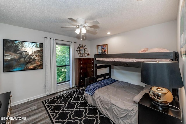 bedroom featuring a textured ceiling, baseboards, visible vents, ceiling fan, and wood finished floors