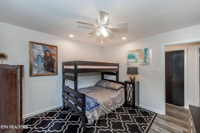 bedroom with a textured ceiling, wood finished floors, baseboards, and recessed lighting