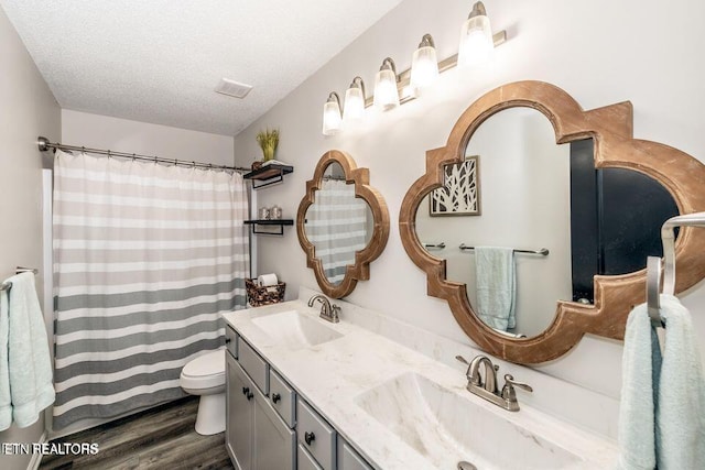 full bathroom with a textured ceiling, toilet, wood finished floors, and a sink