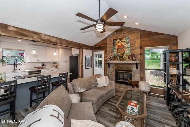 living room featuring a wealth of natural light, vaulted ceiling, ceiling fan, and a textured ceiling
