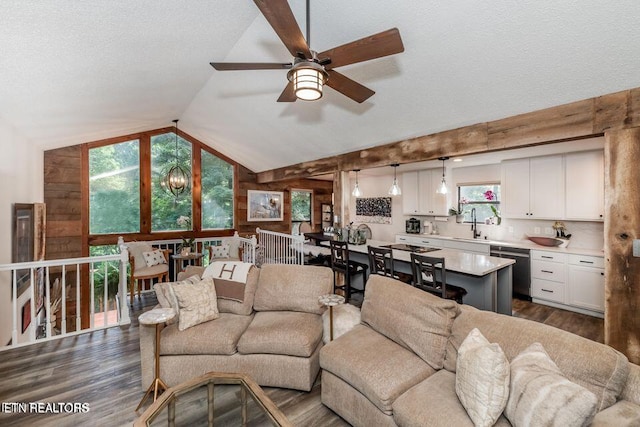 living room featuring a textured ceiling, dark wood-style flooring, ceiling fan with notable chandelier, wood walls, and vaulted ceiling