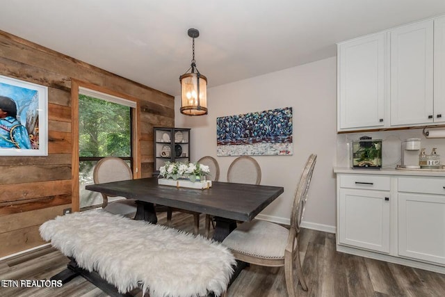 dining space featuring dark wood-type flooring, baseboards, and wooden walls
