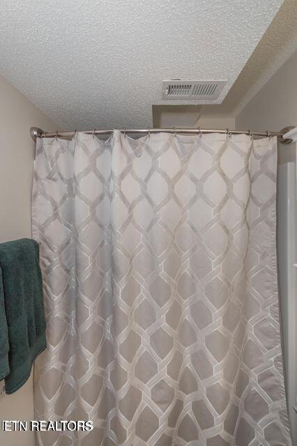 bathroom featuring curtained shower, a textured ceiling, and visible vents