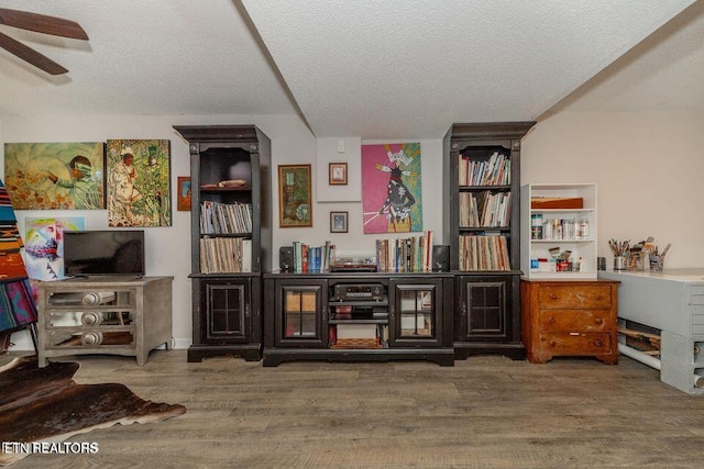 sitting room with a textured ceiling, a ceiling fan, and wood finished floors