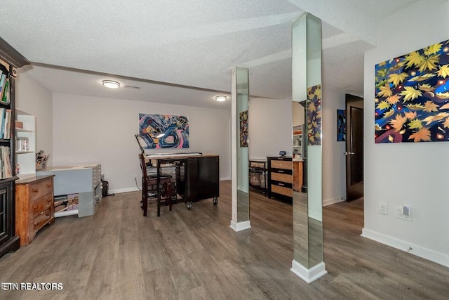 interior space with baseboards, a textured ceiling, and wood finished floors