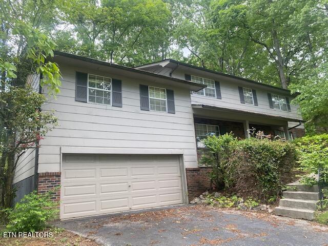 split level home with driveway, brick siding, and a garage