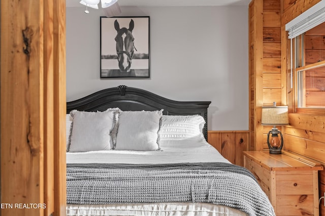 bedroom with wood walls and a wainscoted wall
