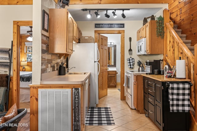 kitchen featuring white appliances, light countertops, light tile patterned floors, track lighting, and a sink