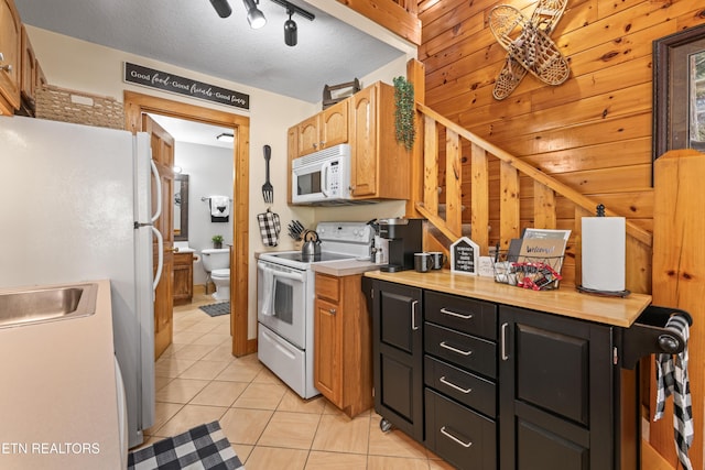 kitchen featuring white appliances, light tile patterned flooring, light countertops, dark cabinetry, and a sink