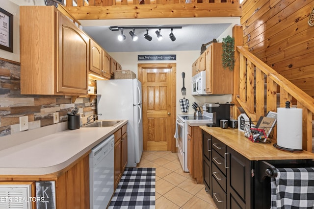 kitchen with white appliances, a sink, track lighting, light tile patterned floors, and dark cabinetry