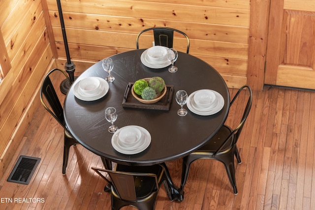 dining space with wood-type flooring and wood walls