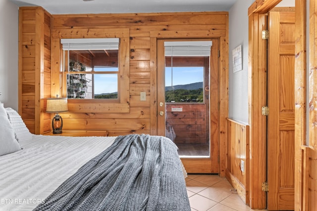 bedroom featuring wood walls, access to outside, and light tile patterned floors