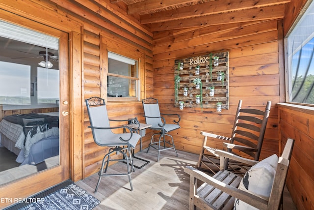 sitting room with wood finished floors, log walls, and beam ceiling