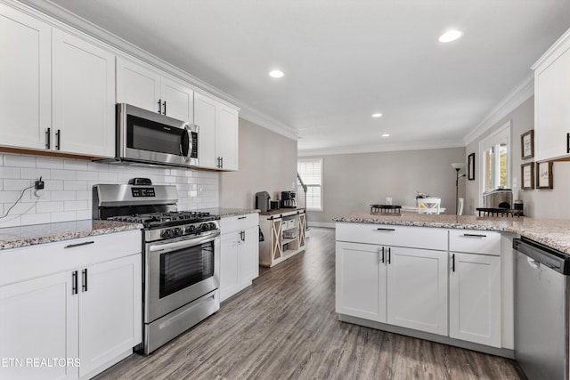 kitchen featuring appliances with stainless steel finishes, crown molding, a peninsula, light wood-style floors, and white cabinets