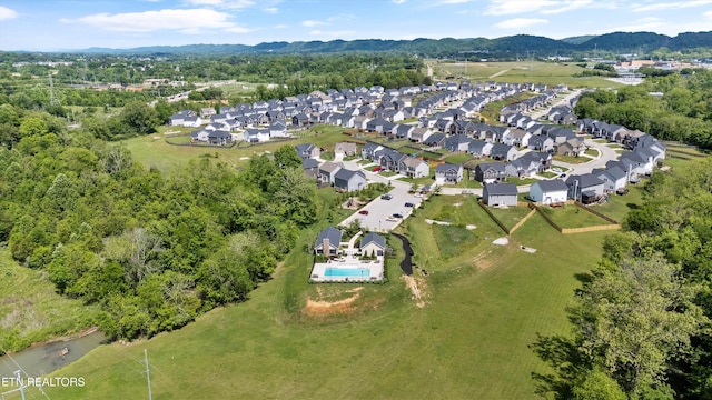 aerial view of property's location featuring mountains, nearby suburban area, and a pool area