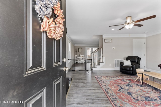 foyer featuring ornamental molding, ceiling fan, wood finished floors, stairs, and baseboards