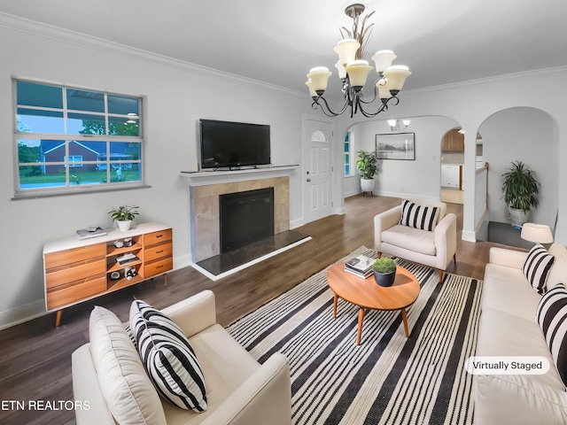 living room with crown molding, wood finished floors, arched walkways, and a tile fireplace
