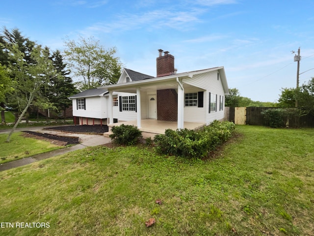 bungalow-style house featuring fence, a chimney, and a front yard