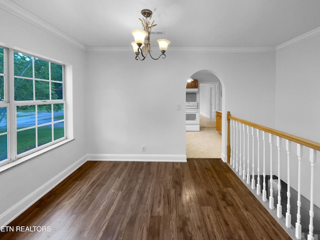 empty room featuring wood finished floors, a healthy amount of sunlight, a notable chandelier, arched walkways, and ornamental molding