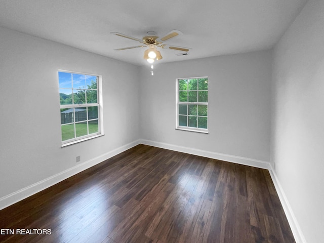 unfurnished room featuring dark wood-type flooring, a ceiling fan, and baseboards