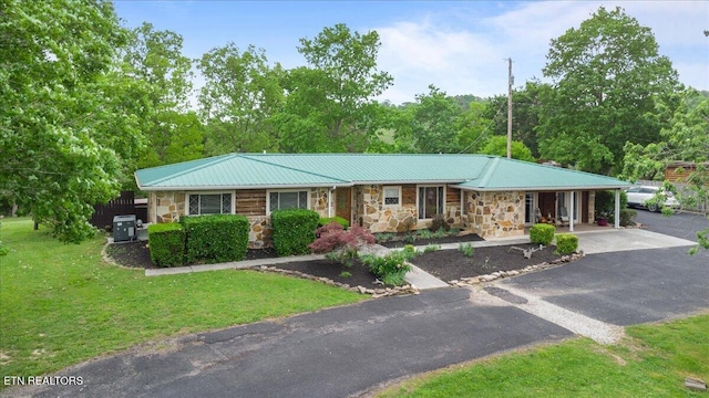 ranch-style house with metal roof, aphalt driveway, stone siding, and a front yard