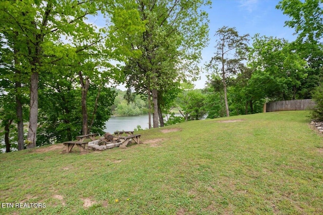 view of yard featuring an outdoor fire pit, fence, and a water view