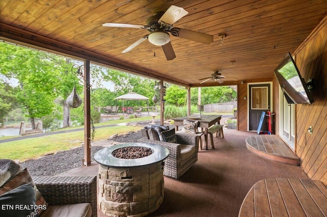 view of patio featuring a fire pit, outdoor dining area, and ceiling fan