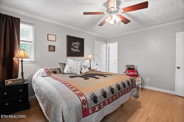 bedroom with a textured ceiling, baseboards, ceiling fan, crown molding, and wood finished floors