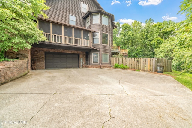6605 Lammie Branch Ln, Knoxville, TN 37938 - back of property with a sunroom, an attached garage, driveway, and brick siding
