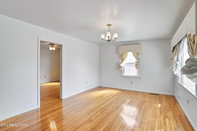 empty room with a chandelier, light wood-type flooring, baseboards, and a ceiling fan